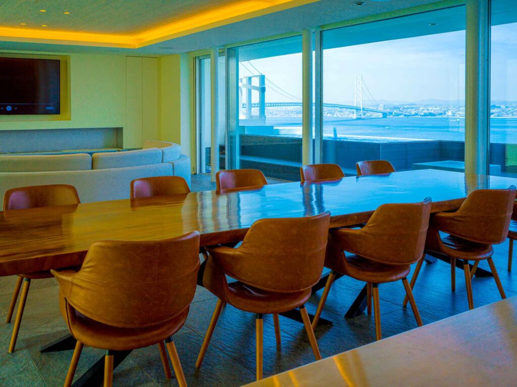 2階にあるモダンなキッチンアイランドです。アイランドは、木製のパネルとステンレスのカウンタートップでできており、3つの蛇口とIHクッキングヒーターが備わっています。上からは3つの黒いペンダントライトが吊り下がっており、奥の壁はダークグレーで統一されています。